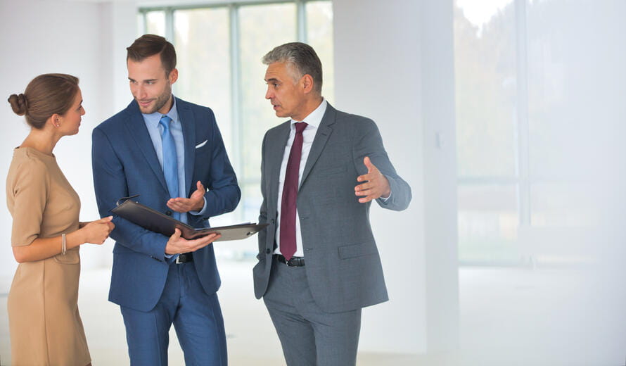Smiling mature businessman gesturing to colleagues at new office