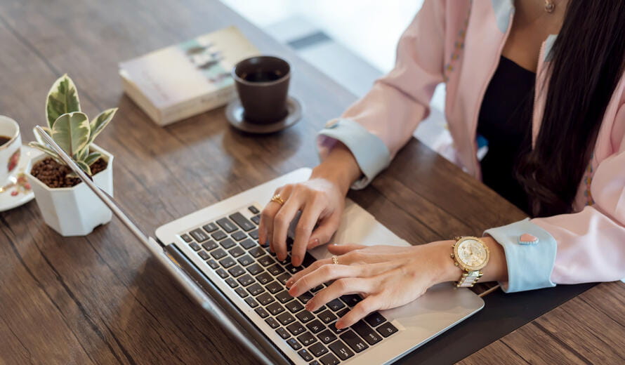 Close-up of a young businesswoman typing on a laptop, highlighting professional work and focus.